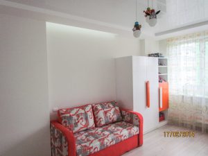 Капітальний ремонт квартири 80 м² - дитяча кімната, виконана у світлих кольорах, має ніші з підсвіткою, та диван у яскравому сіро-біло-оранжевому кольорі